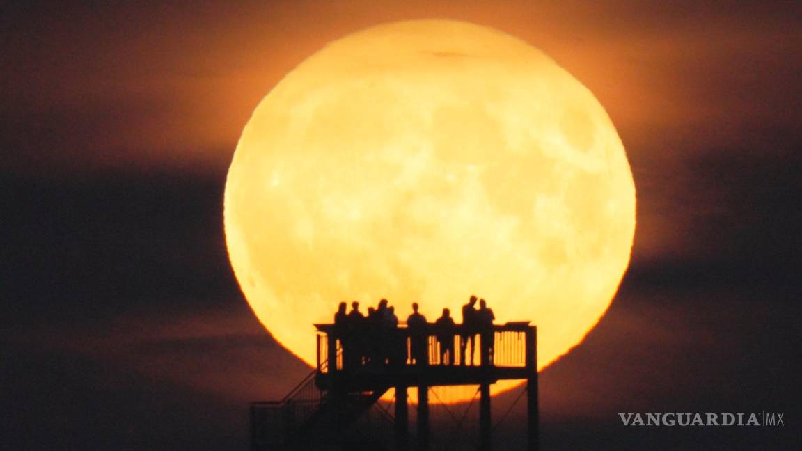 $!La gente ve salir la luna desde la torre de observación en Syke, Alemania, el miércoles 13 de julio de 2022.