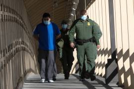 Dos migrantes centroamericanos (i) caminan mientras son deportados bajo el programa reactivado “Quédate en México” por el puente Internacional Reforma en Ciudad Juárez, estado de Chihuahua (México). EFE/Luis Torres
