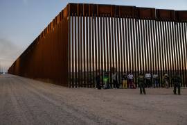 Un grupo de migrantes es detenido para ser procesado después de entregarse en un muro fronterizo de Estados Unidos con México, en Yuma, Arizona.