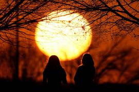 Dos personas miran el atardecer en un parque, en un día inusualmente cálido, el 25 de febrero de 2024, en Kansas City, Misuri.