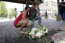 Brooke y Matt Strauss, que se casaron el domingo, hacen una pausa después de dejar sus ramos de boda en el centro de Highland Park, Illinois, un suburbio de Chicago, cerca de la escena de la masacre.