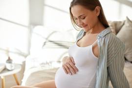Una mujer embarazada observa su vientre con emoción.