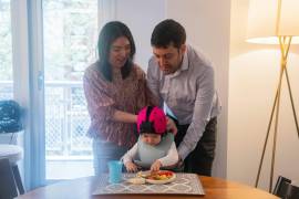El Dr. Brenden Lake, psicólogo de la Universidad de Nueva York, y su esposa, la Dra. Tammy Kwan, con su hija de 1 año, Luna, que lleva un sombrero rosa suave en la cabeza con una cámara liviana tipo GoPro.