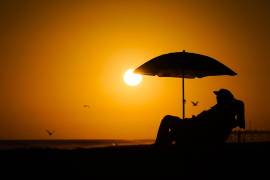 Una persona descansa bajo una sombrilla durante la puesta del sol en Newport Beach, California.