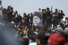 Un manifestante sostiene un cartel que representa al clérigo chiíta Muqtada al-Sadr en un puente que conduce hacia el área de la Zona Verde en Bagdad.