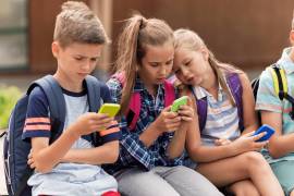 Grupo de niñas y niños sentados utilizando sus ‘smartphones’.