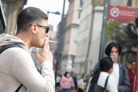 Un hombre fuma un cigarro sobre la calle Madero en el Centro Histórico en la CDMX.