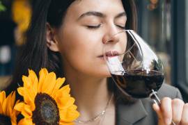 Mujer olfateando una copa de vino tinto con atención.
