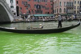 Un gondolero impulsa una góndola a lo largo de un parche de líquido verde fosforescente visto en el Gran Canal cerca del Puente de Rialto, en Venecia, Italia, el 28 de mayo de 2023.