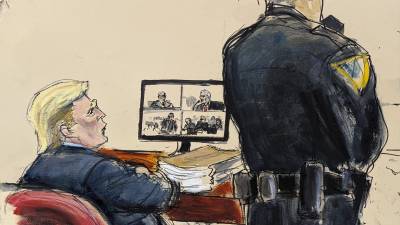 El expresidente Donald Trump sentadoa en la mesa de la defensa mientras David Pecker, que se muestra en la pantalla de video, testifica sobre Karen McDougal en el tribunal penal de Manhattan.