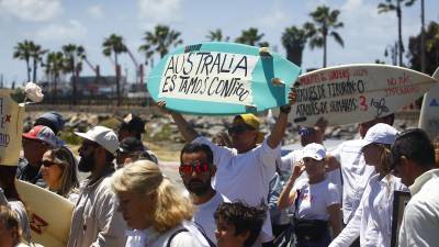 Personas sostienen tablas de surf durante una manifestación para exigir justicia por el asesinato de tres surfistas extranjeros este domingo, en la ciudad de Ensenada.