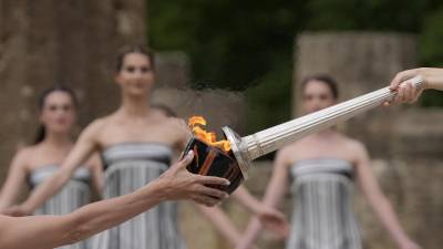 La actriz Mary Mina, quien interpretó a una sacerdotisa, a la derecha, encendió una antorcha durante la ceremonia oficial para los Juegos Olímpicos de París.