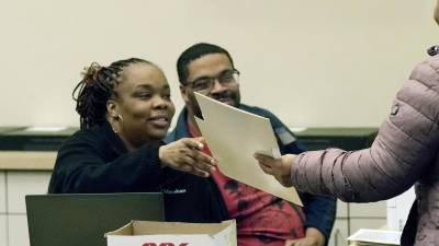 Una votante, a la derecha, recibe una papeleta durante la votación anticipada en el ayuntamiento de Warren en Warren, Michigan.