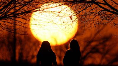 Dos personas miran el atardecer en un parque, en un día inusualmente cálido, el 25 de febrero de 2024, en Kansas City, Misuri.