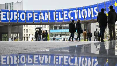 La gente pasa junto a anuncios para las próximas elecciones de la UE de 2024 frente al edificio del Parlamento Europeo en Bruselas, Bélgica.