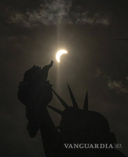 $!The moon partially covers the sun behind the Statue of Liberty during a total solar eclipse on the Liberty Island, Monday, April 8, 2024, in New York. (AP Photo/Yuki Iwamura)