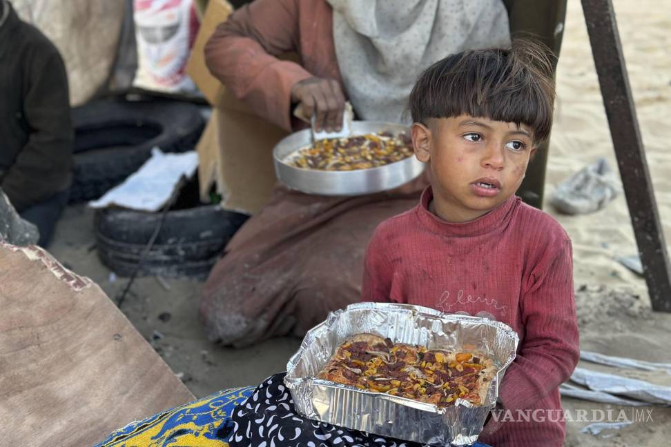 $!Un niño come un plato del Iftar, que marca la ruptura del ayuno en ramadán en Rafah, Gaza.