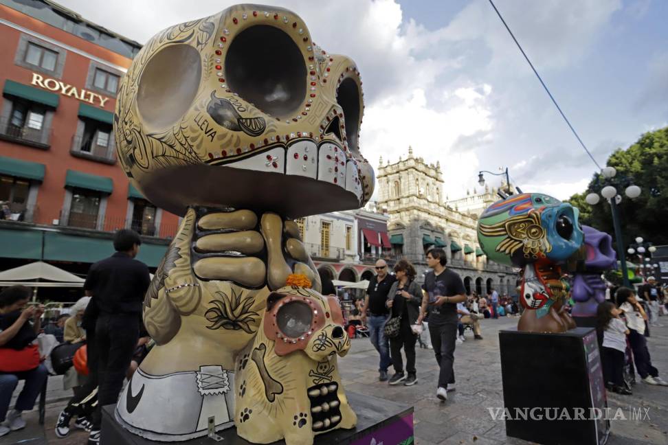 $!Visitantes observan piezas de la exposición Me lleva la huesuda en el zócalo de la ciudad de Puebla (México).