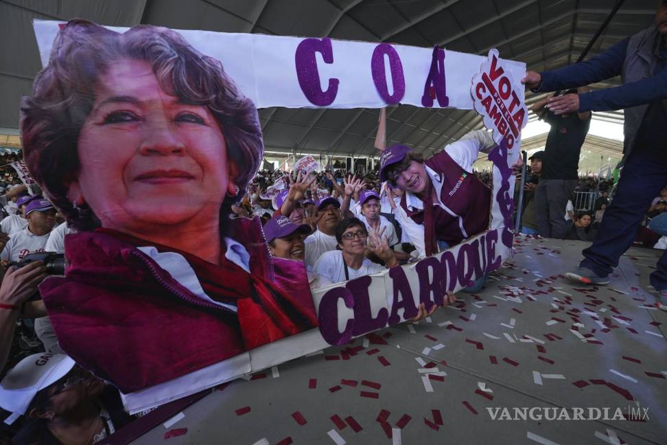 $!Delfina Gómez, candidata del partido Morena a la gubernatura del Estado de México posa junto a una pancarta con su imagen en un evento de campaña.