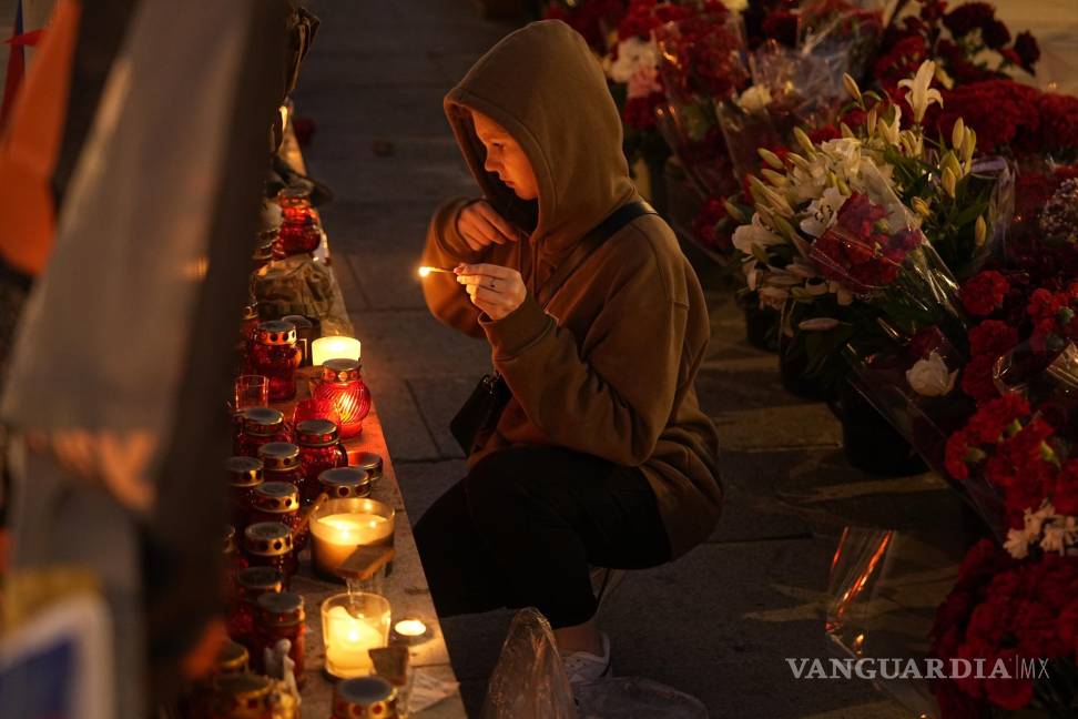 $!Una joven se persigna mientras enciende una vela en un monumento para los miembros del grupo militar del Grupo Wagner muertos en un accidente aéreo.