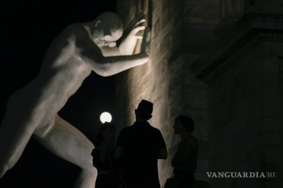 $!La luna llena, vista detrás de la escultura Mr Arbitrium, del artista Emanuele Giannelli, que se apoya en el Arco de la Paz, en Milán, Italia, el 13 de julio de 2022.