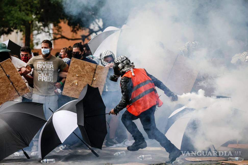$!Un manifestante pro palestino devuelve un bote de gas lacrimógeno a la policía después de que cayó contra manifestantes en la Universidad del Sur de Florida.