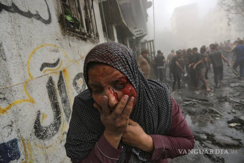 $!Una mujer palestina herida sale corriendo tras ataques aéreos israelíes sobre su vecindario en la Ciudad de Gaza, el 23 de octubre de 2023.