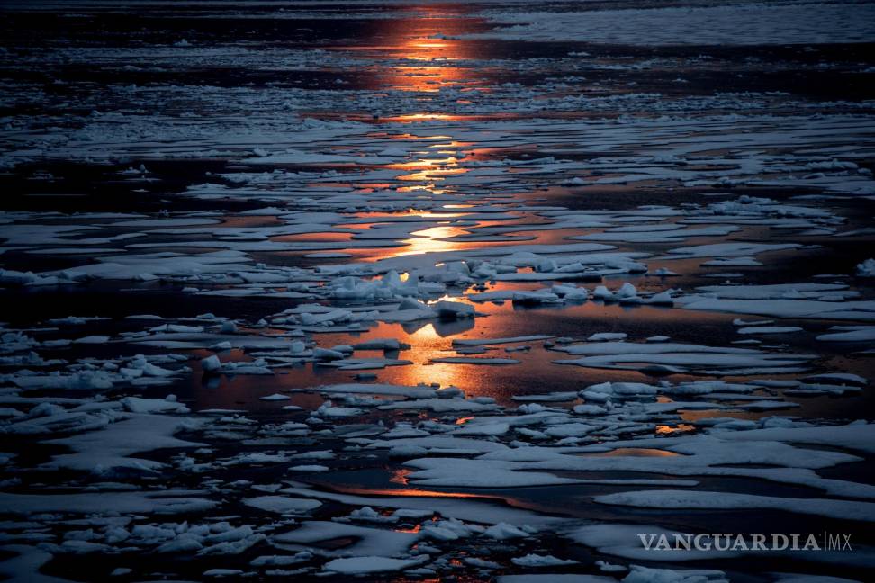 $!El sol de medianoche brilla a través del hielo marino a lo largo del Pasaje del Noroeste en el archipiélago ártico canadiense, el domingo 23 de julio de 2017. Cuando está cubierto de nieve y hielo, el Ártico refleja la luz solar y el calor. Pero esa manta está menguando. Y a medida que se derrite más hielo marino en el verano, “estás revelando superficies oceánicas realmente oscuras, como una camiseta negra”, dice la científica del hielo Twila Moon. Como la ropa oscura, los parches abiertos del mar absorben el calor del sol más fácilmente. AP/David Goldman