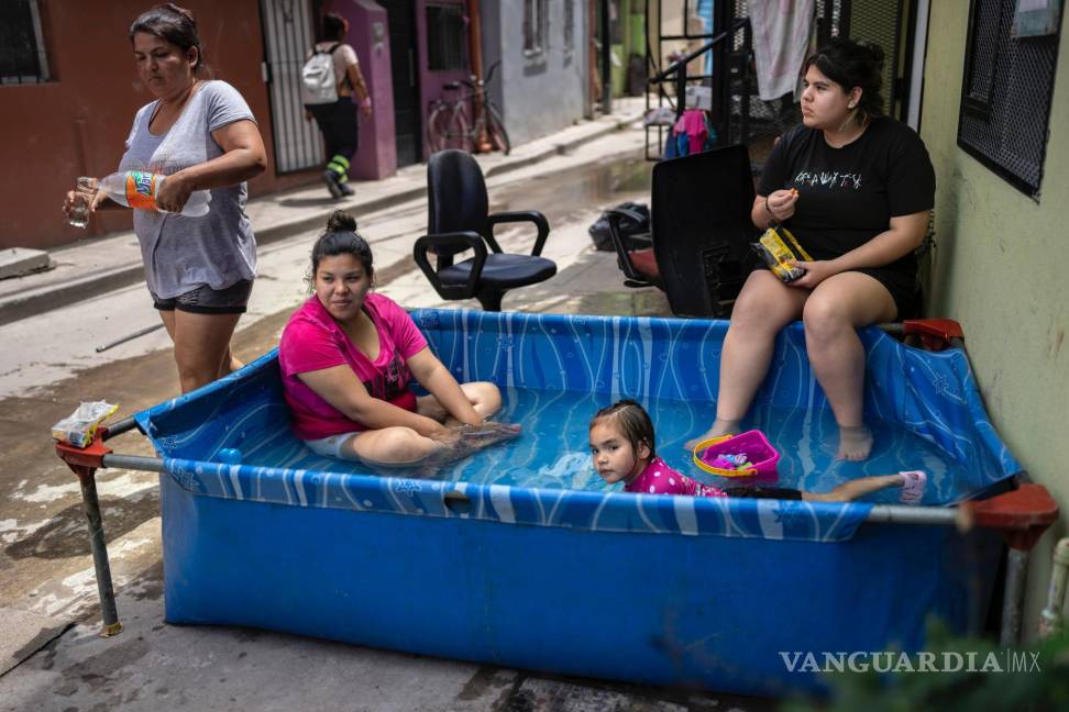 $!Miembros de la familia Sánchez se refrescan en una piscina de plástico fuera de su casa en el barrio Padre Carlos Múgica de Buenos Aires, Argentina.