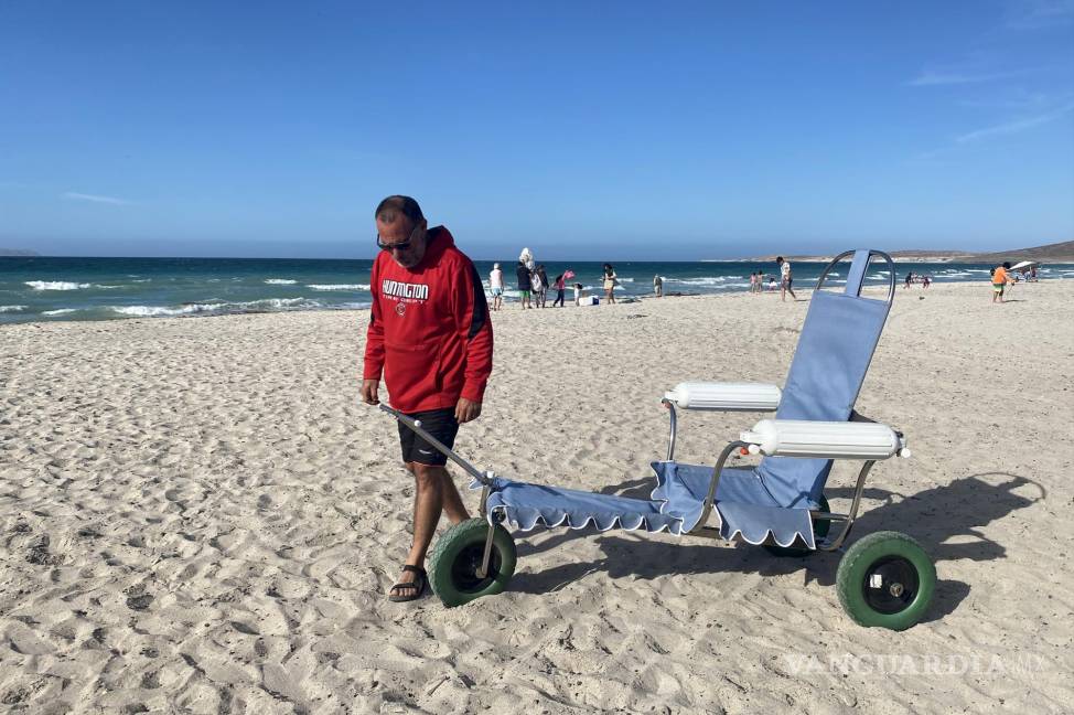 $!El experto en mecánica automotriz, Andrés Mata, posa junto a una silla de ruedas anfibia en una playa del balneario de La Paz (México).