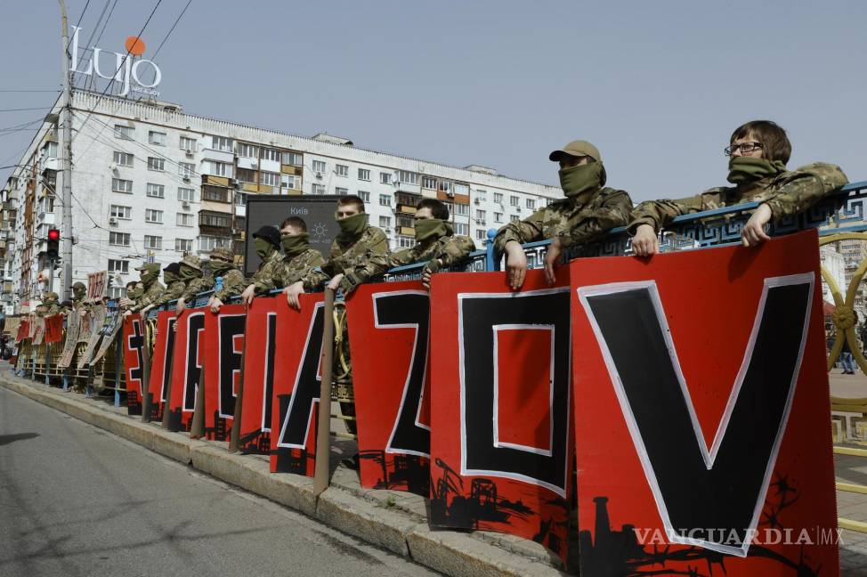 $!Manifestantes con uniforme militar sostienen pancartas con las palabras “Liberen a Azov” durante una manifestación en el centro de Kiev, Ucrania.