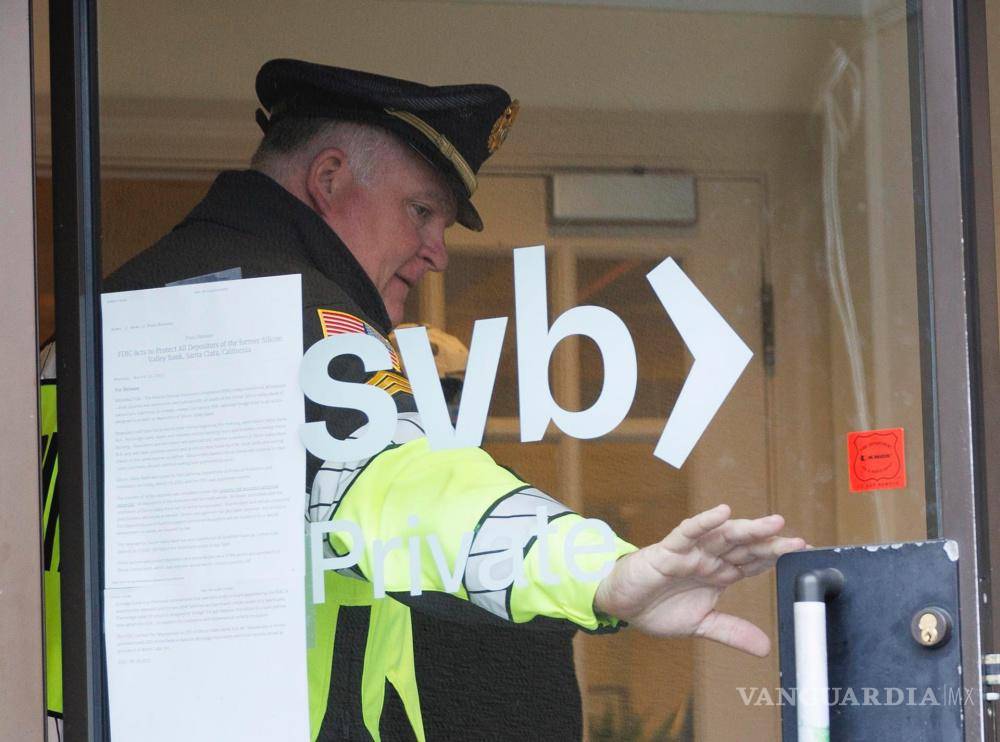 $!Un oficial de policía sostiene la puerta abierta para un cliente cuando ingresa a una sucursal de Silicon Valley Bank en Wellesley, Massachusetts.