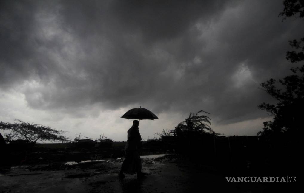 $!Una persona sostiene un paraguas mientras las nubes oscuras se ciernen sobre el distrito de Balasore en Odisha, India, el martes 25 de mayo de 2021. AP