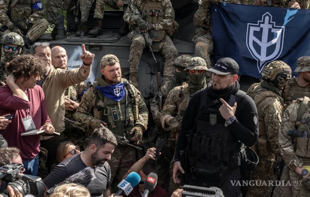 $!Denis Kapustin, a la derecha vestido de negro, identificado como neonazi por la Liga Antidifamación, es entrevistado por reporteros en el noreste de Ucrania.