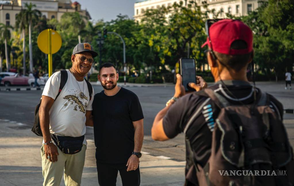 $!Elián González, en el centro, posa con un peatón que le pidió una foto mientras da una entrevista en La Habana, Cuba, el jueves 27 de junio de 2023.