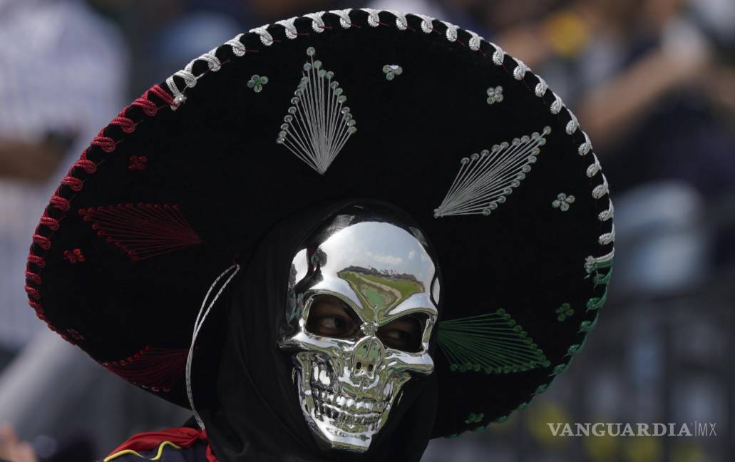 $!Un aficionado con una máscara de calavera plateada y un sombrero de charro aplaude antes del inicio de la carrera de autos del Gran Premio de México.