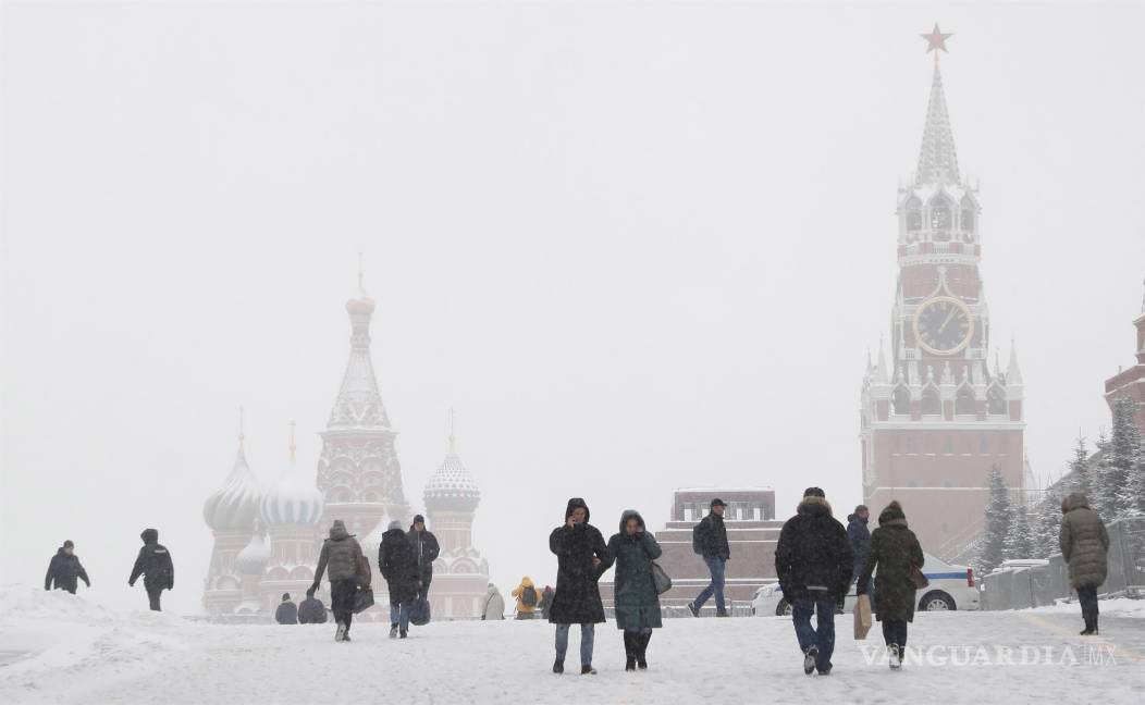 $!Las personas que llevaban máscaras protectoras contra el Covid-19 caminan por la Plaza Roja fuera del Kremlin durante una nevada en Moscú, Rusia. EFE/EPA/Maxim Shipenkov
