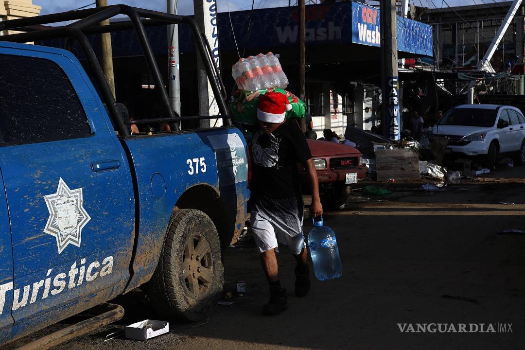 $!Fotografía que muestra a una persona mientras con objetos saqueados una tienda de autoservicio por el paso del huracán Otis en Acapulco, en Guerrero (México).