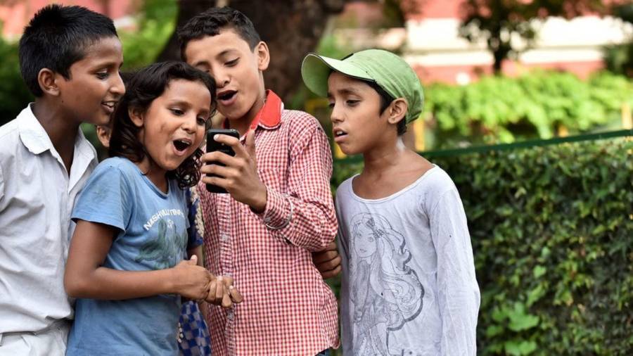 Niños en la Escuela San Columba en Delhi, India, se toman fotos con su smartphone.