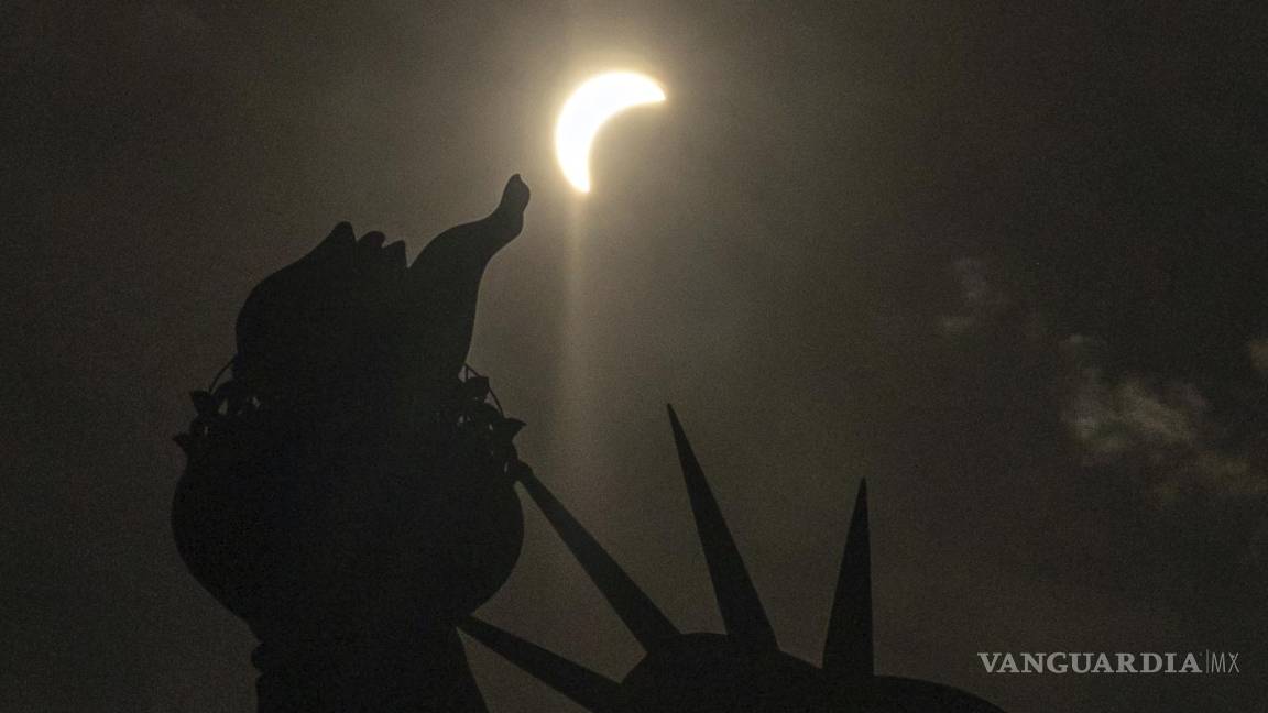 $!The moon partially covers the sun behind the Statue of Liberty during a total solar eclipse on the Liberty Island, Monday, April 8, 2024, in New York. (AP Photo/Yuki Iwamura)