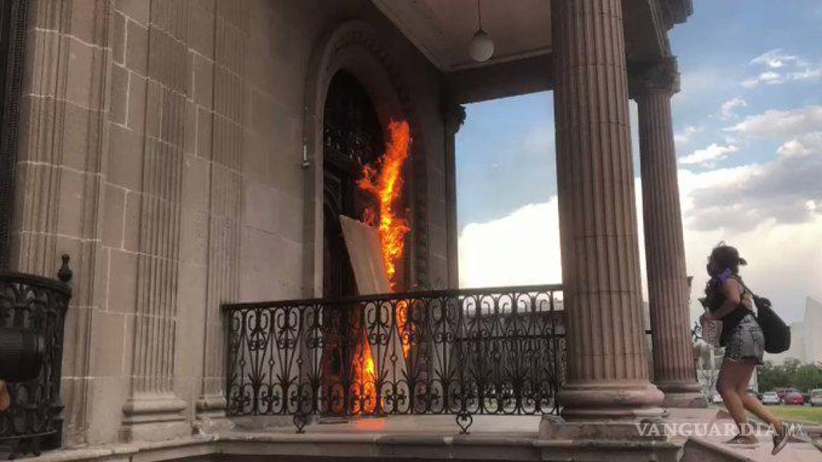 Protestan por feminicidios en NL, prenden fuego a puerta del Palacio de Gobierno