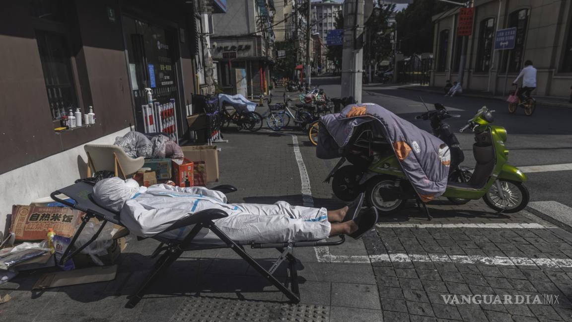 $!Un repartidor con equipo de protección duerme la siesta en la calle en medio del confinamiento por el COVID-19 en Shanghái, China.