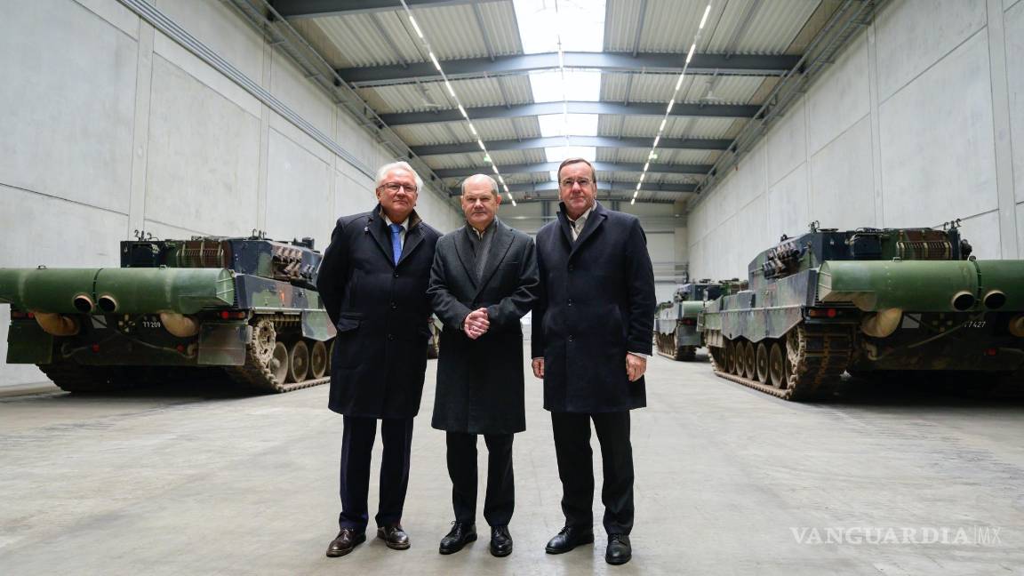 $!Armin Papperger director ejecutivo de Rheinmetall (i), el canciller alemán Olaf Scholz (c) en una sala con los principales tanques de batalla Leopard 2A4.