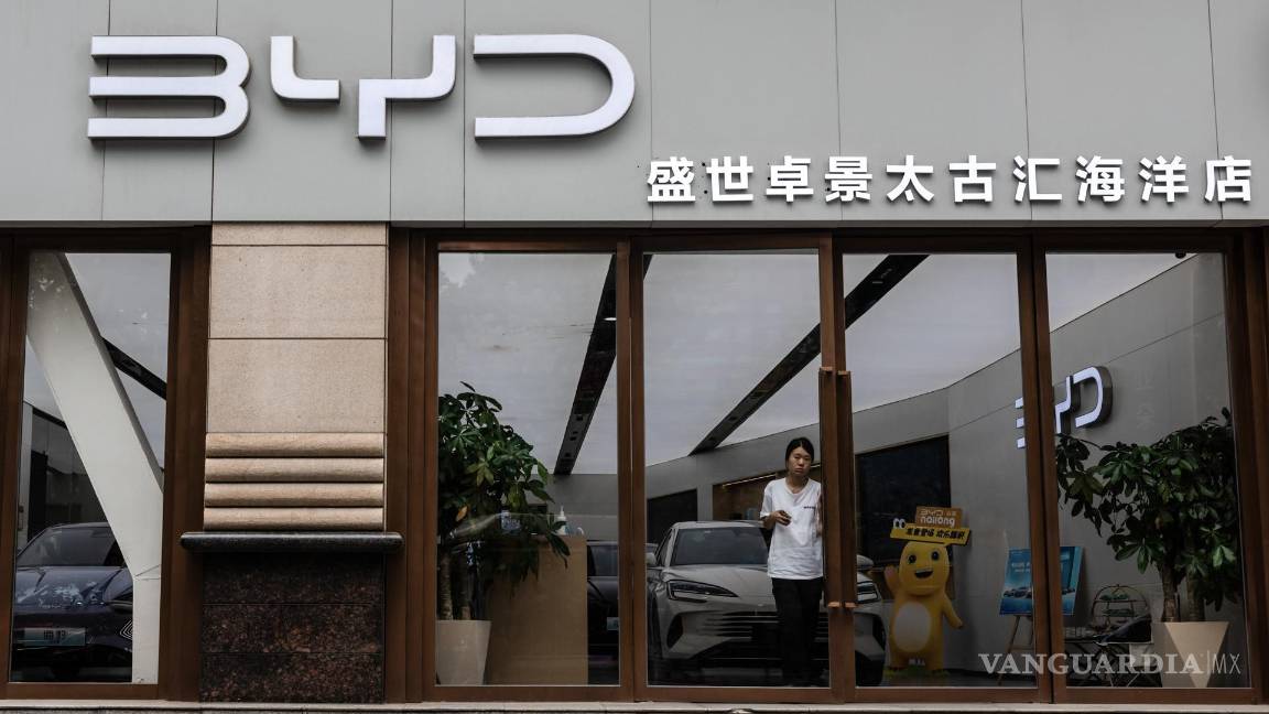 $!Una mujer sale de una tienda del fabricante de vehículos eléctricos BYD, en Shanghai, China.