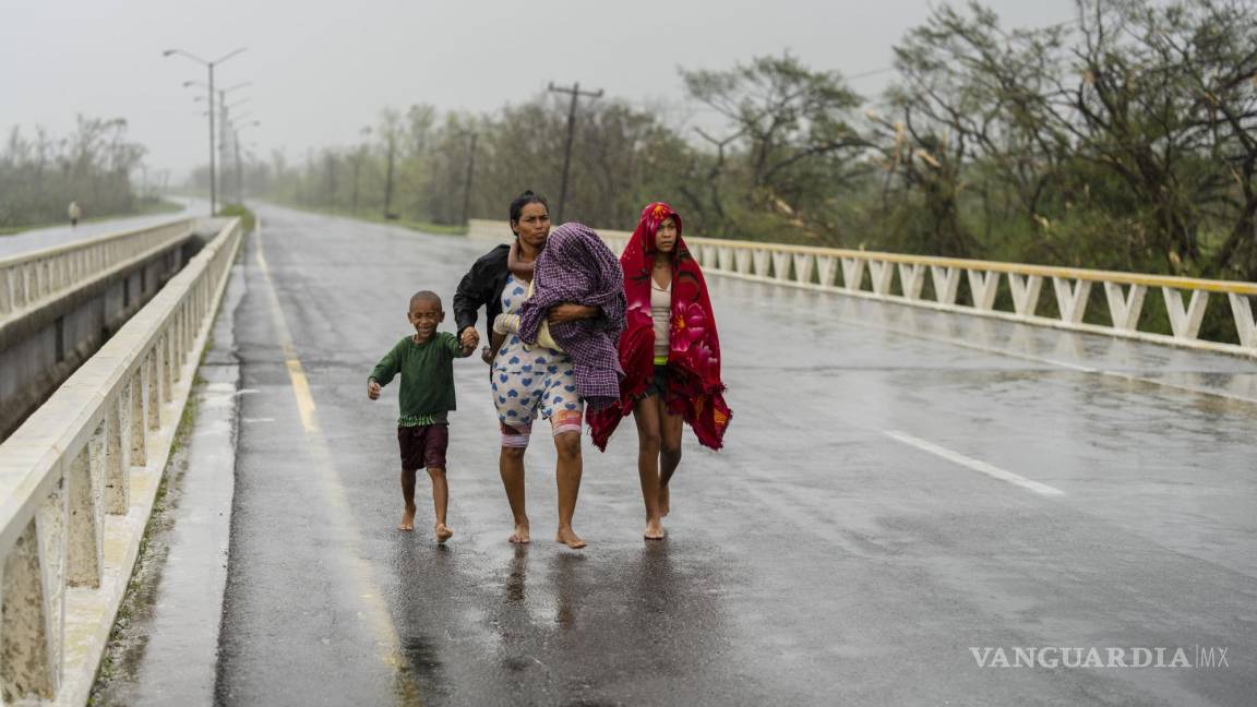 $!Una familia camina bajo la lluvia en busca de refugio luego de que el huracán Ian anegó su vivienda en Pinar del Río, Cuba, el 27 de septiembre de 2022. (AP Foto/Ramón Espinosa)