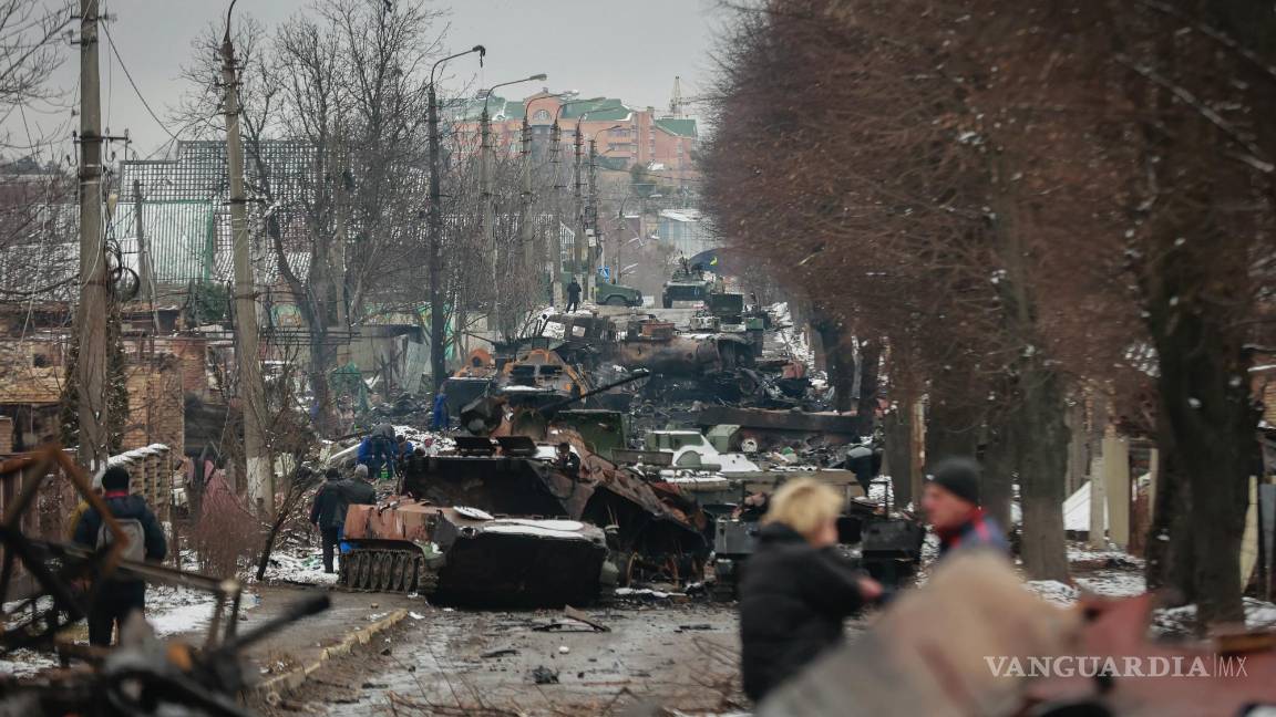 $!Varias personas observan los restos de vehículos militares rusos en una calle de la ciudad de Bucha, cerca de la capital de Ucrania, Kiev, el 1 de marzo de 2022.