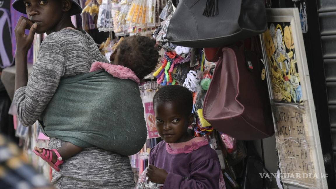 $!Una mujer sin máscara con dos niños camina por la concurrida parada de taxis de Bara en Soweto, Sudáfrica.