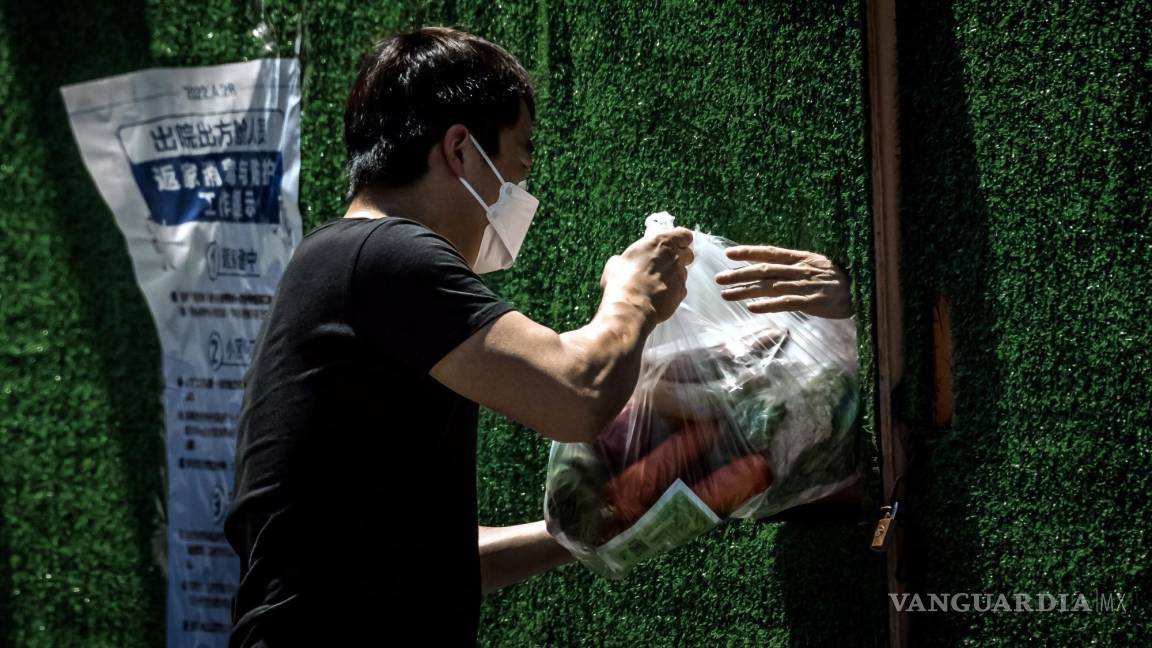 $!Un repartidor pasa comida a la persona en cuarentena a través del agujero en la cerca en medio del bloqueo de Covid-19 en curso en Shanghái, China.