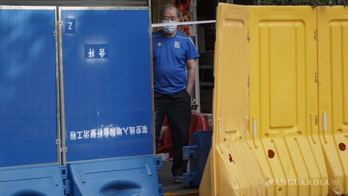 $!Un hombre se para detrás de las barreras de plástico antes de que se levante el cierre en Shanghái, China.