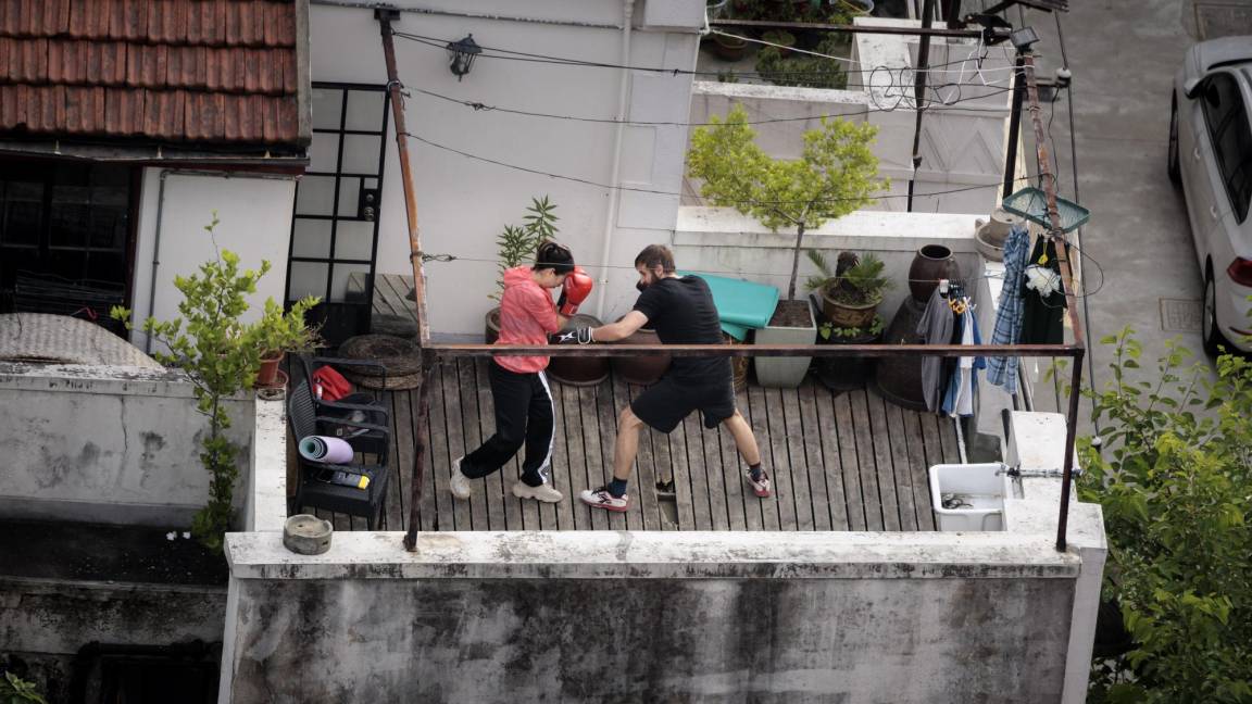 $!Una pareja practica boxeo en su balcón en un complejo residencial en Shanghái, China.